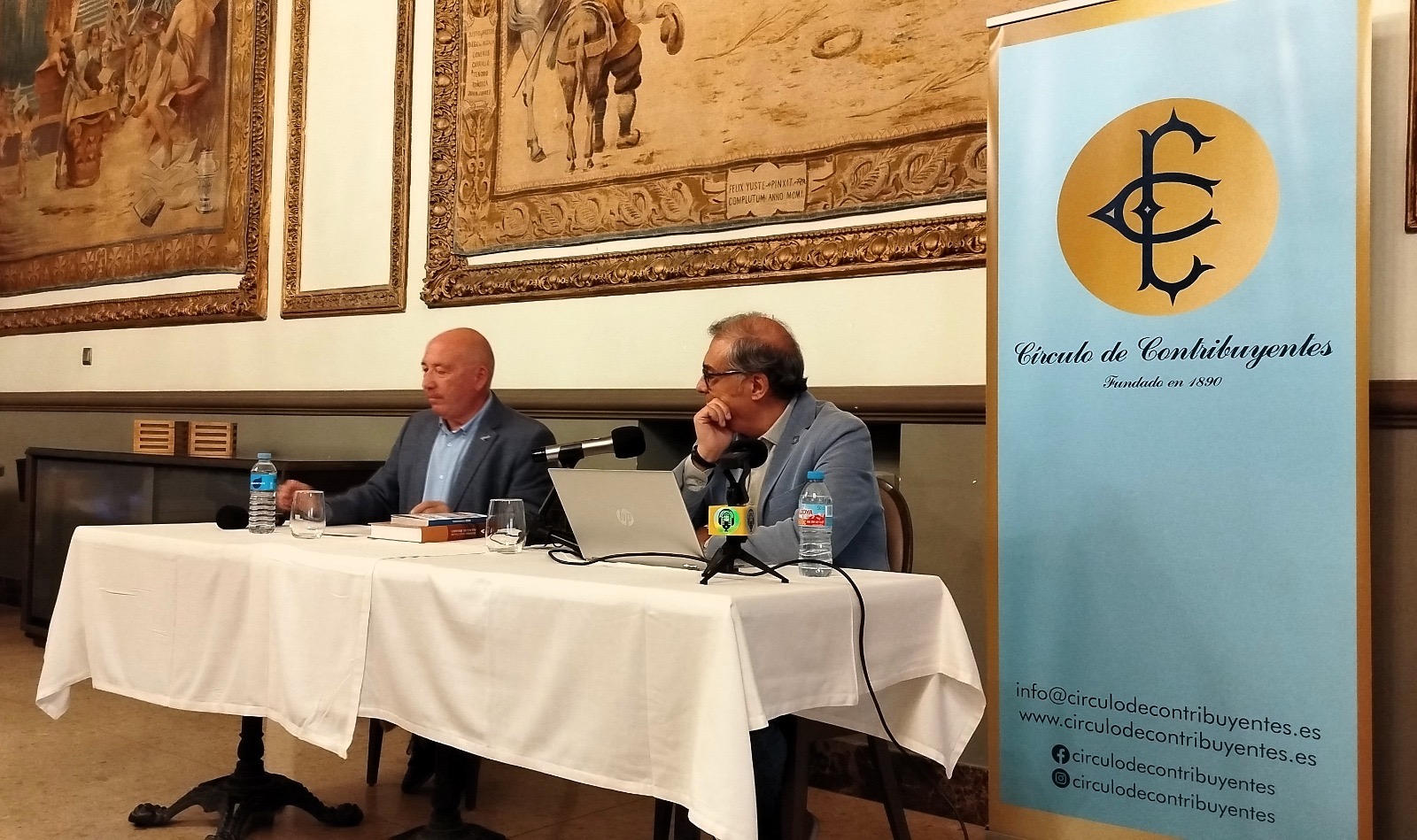 La mesa de la conferencia junto al emblema del Círculo y las obras del Salón de Tapices
